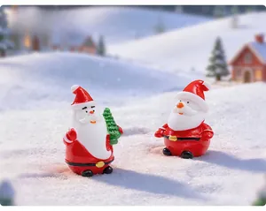 Close-up of two miniature resin Santa Claus figurines with a mini Christmas tree decor