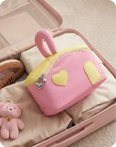 Détail de la trousse à maquillage bicolore avec breloques cœur dans une valise rose