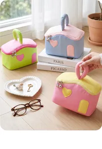 Détail de la trousse à maquillage en forme de maison avec texture matelassée et zip cœur
