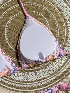 Detail of floral bikini top featuring removable pads and adjustable pink halter straps