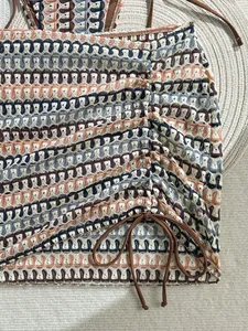 Detail of crochet beach skirt with wavy hollow knit pattern and side drawstring ties