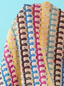 Detailed macro shot of bohemian hollow crochet fabric with colorful geometric patterns