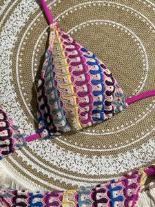 Close-up of bohemian crochet bikini set with colorful wave patterns on a beach mat