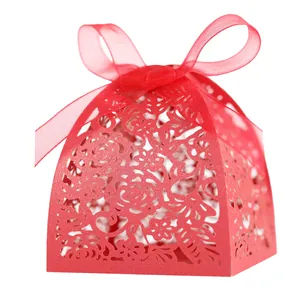 Detail of red hollow laser-cut wedding favor box with rose patterns and ribbon