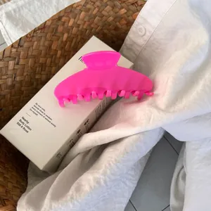 Macro view of a neon pink acetate hair claw clip on white fabric with natural lighting