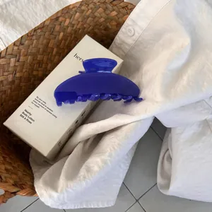 Close-up of a large royal blue hair claw clip with a glossy finish on a white shirt