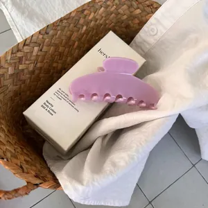 Close-up of a large purple matte hair claw clip on a gift box inside a woven basket