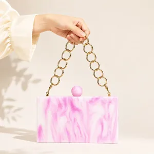 Detail of pink marble acrylic clutch with gold ring handle and spherical ball clasp