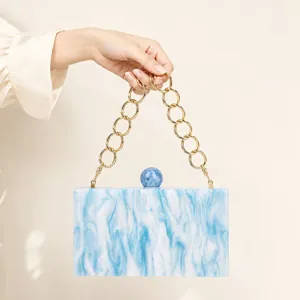 Detail of blue marble acrylic clutch bag with large gold metal ring handle and ball lock