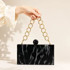 Detail of marble pattern evening bag with golden chain strap and round spherical clasp