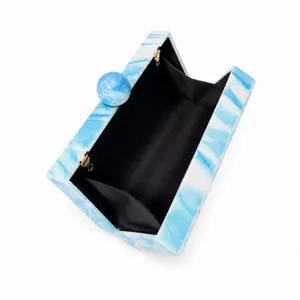 Detailed interior of marble acrylic clutch bag featuring spherical clasp and gold hinges