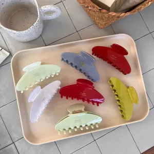 Set of colorful acetate hair claw clips with gold lettering on a minimalist tray