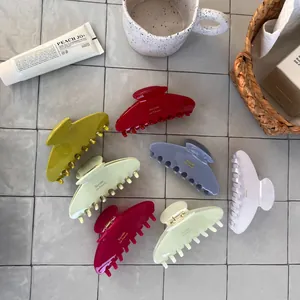 Detailed close-up of colorful acetate hair claws with gold-stamped logo on sleek resin