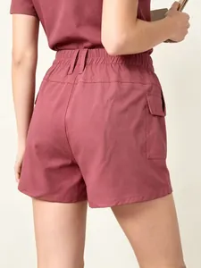 Detail of high-waist cargo shorts featuring elastic waist and utility pocket in dark red
