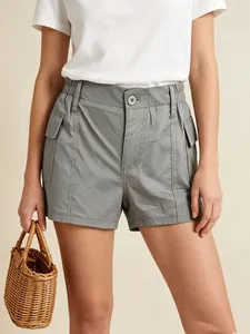 Detail of grey high-waisted utility shorts with elastic waist and cargo flap pockets