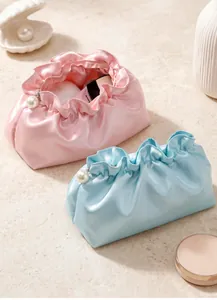 Detail of satin cloud makeup bags with elegant ruffle edges and luxury pearl zippers
