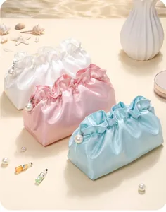 Detail of satin cloud makeup bags with ruffled edges and pearl zipper charms