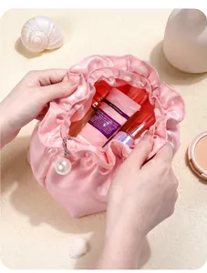 Detail view of pink satin cosmetic pouch showing spacious interior with pearl zipper pull