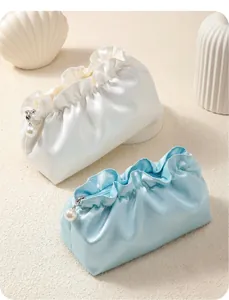 Detail of silk ruffle makeup bags with pearl zipper charms in white and light blue
