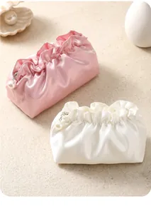 Detail of pink and white satin cloud bags with elegant oversized pearl zipper puller