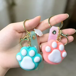 Close-up of cute cat paw keychains in mint green and pink silicone with gold hardware