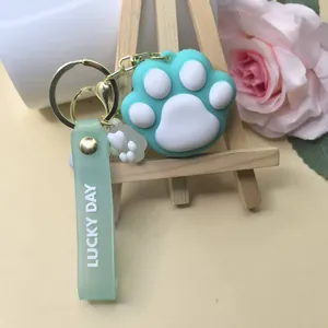 Detail of mint green cat paw keychain with Lucky Day strap on a wooden stand