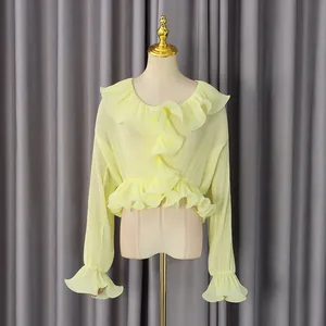 Detail of light yellow pleated shirt featuring ruffled edges and layered flare sleeves