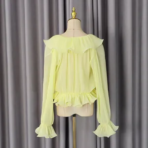 Detail of light yellow pleated chiffon top showing ruffles and refined fabric texture