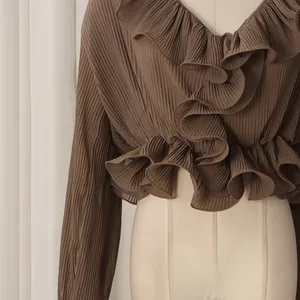 Detailed view of the layered ruffles and fine pleated texture on the brown blouse