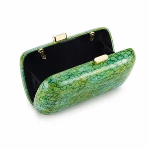 Detail view of acrylic green marble clutch bag with gold clasp and black fabric interior