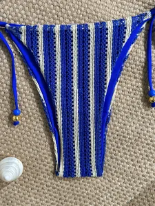 Detail of crochet bikini bottom with blue stripes and decorative gold beads on side ties