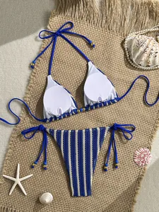 Detailed flat lay of a blue striped crochet bikini with beach decor and gold bead ties