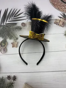 Detail of black mini witch hat headband with gold sequins, bow, and soft black feathers
