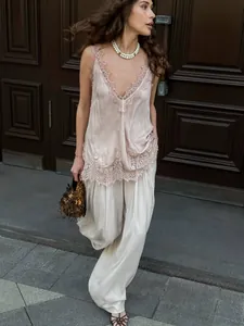 Detail of V-neck lace trim camisole paired with white satin trousers in an elegant street setting
