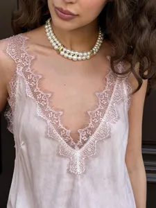 Close-up of the delicate eyelash lace trim and V-neckline on the pink satin tank top