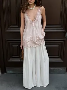 Detailed lace trim on a dusty pink satin camisole top paired with light trousers