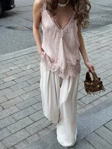 Close-up of pink satin V-neck camisole with delicate lace trim and pearl necklace