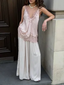 Detailed view of the delicate lace embroidery on a pink silk camisole V-neck top