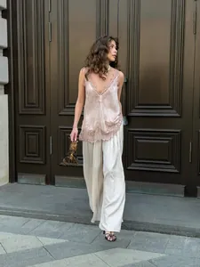 Detail of pink silk camisole with eyelash lace trim paired with white satin trousers