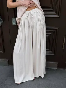 Detail of beige pleated wide-leg trousers with elastic drawstring waist and satin texture