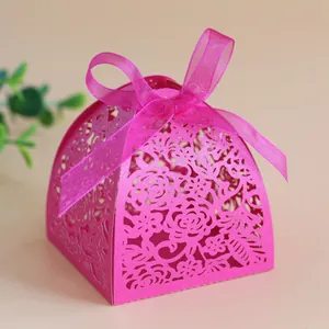 Close-up of laser-cut rose pink favor box with floral patterns and organza ribbon