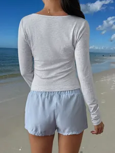 Back view of light grey slim-fit long sleeve t-shirt and blue striped shorts at the beach