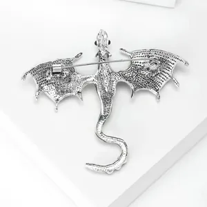 Silver dragon brooch with secure rotating pin clasp on white geometric pedestal