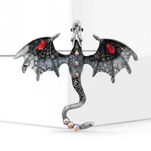 Detailed macro of a silver dragon brooch with black enamel and red gemstone wings