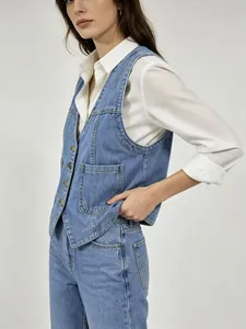 Détail du gilet en jean cintré avec boutons métalliques et poches sur chemise blanche