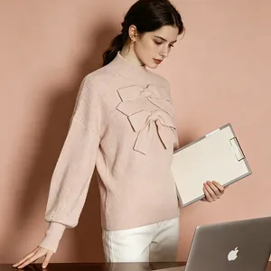 Detail of pink turtleneck knit sweater with large bow accents and ribbed texture