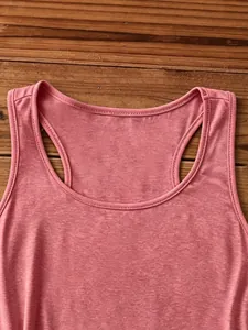 Detail view of pink racerback tank top neckline on dark wood grain background