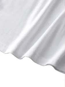 Detail of white cotton vest showing soft knit texture and durable double-stitch hemline