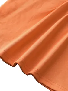 Detail shot of orange knit vest hem featuring high-quality double-needle stitching and soft cotton texture