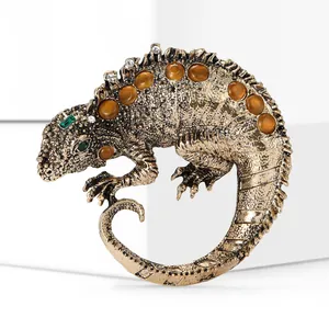 Macro detail of vintage alloy lizard brooch featuring orange gems and golden texture